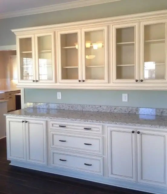 Cream glazed kitchen cabinets with glass-front uppers and granite countertop, from a cabinet maker in Warner Robins